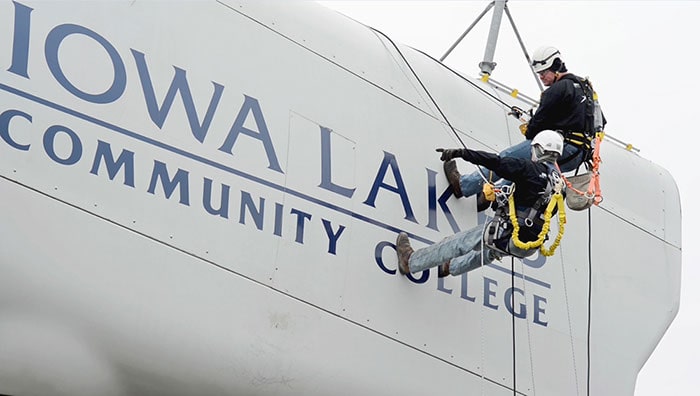 Two students on the side of wind energy equipment at Iowa Lakes Community College