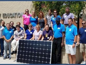 Workshop participants posing with a solar panel