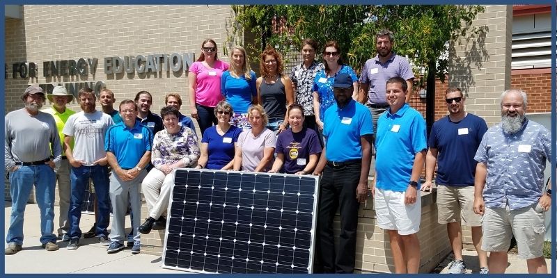 Workshop participants posing with a solar panel