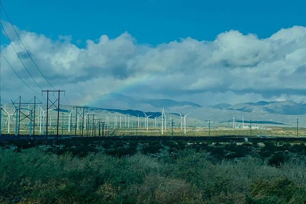 Wind turbines with electrical towers, clouds and rainbow