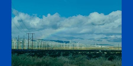 Wind turbines and electrical with clouds and rainbow.