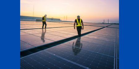 Workers on solar panels at sunset.