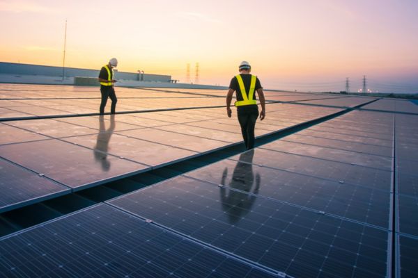 Workers on solar panels at sunset.