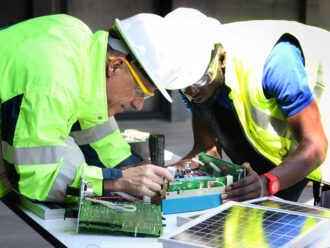 Two electrical engineers working with electronic circuit board and solar cells