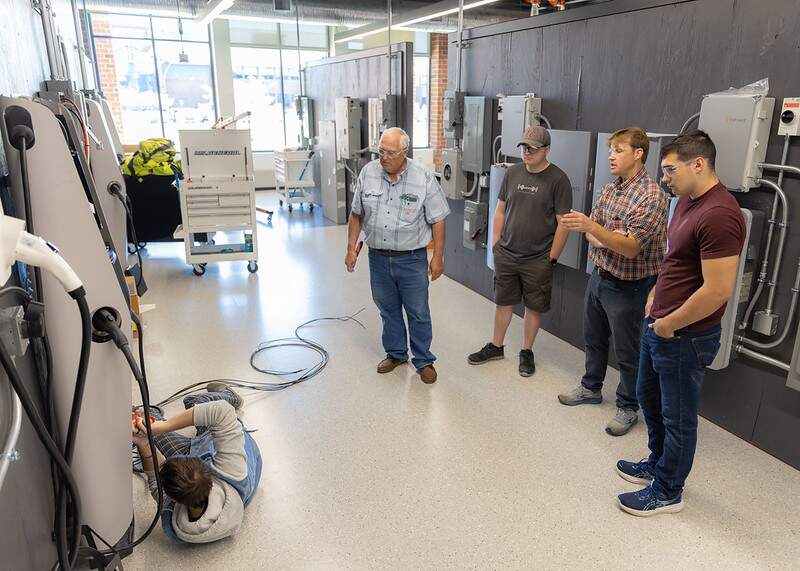 Student connecting a conductor into a terminal block of a level 2 EV charger.