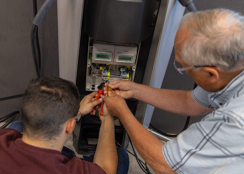 Students testing how secure a conductor was installed into a terminal block in EV charger.