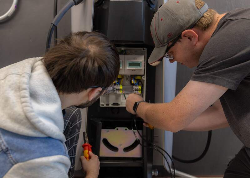 Students verifying exposed conductor from the insulation the cut from wire is enough to be properly terminated in an EV charger.