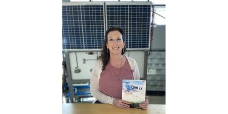 Dr. Jennifer Clemons CREATE Co-PI with solar panels and energy textbook.