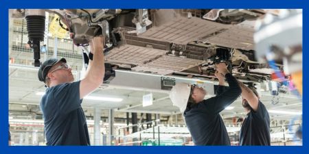 Workers install battery packs in a BMW X5 in South Carolina. A new battery plant under construction nearby will supply BMW factories. (Credit: BMW)