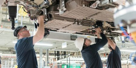 Workers install battery packs in a BMW X5 in South Carolina. A new battery plant under construction nearby will supply BMW factories. (Credit: BMW)