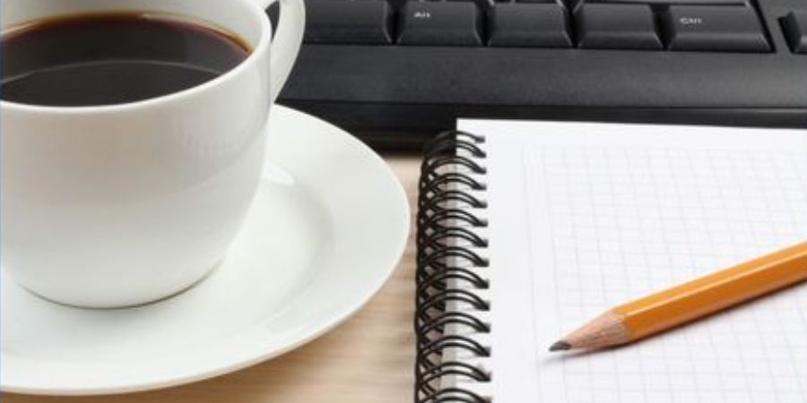 Coffee cup, keyboard, paper and pencil